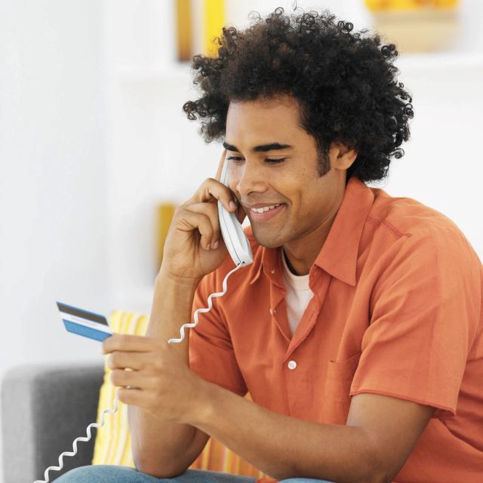 A man talking on the phone while holding his credit card.